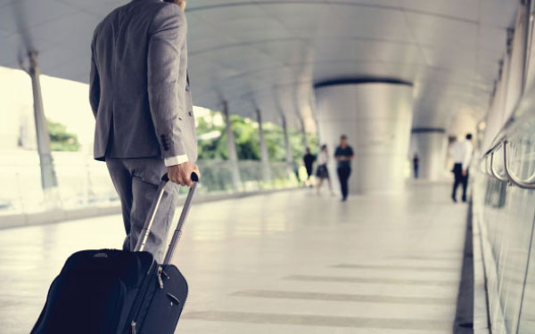 A businessman walking through an airport with luggage A businessman walking through an airport with luggage