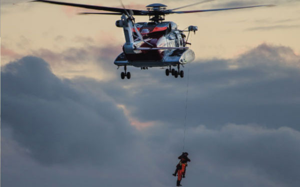 A rescue helicopter pulling up a person A rescue helicopter pulling up a person